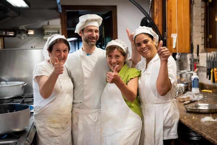Eine Gruppe lächelnder Köche in einer einfach eingerichteten Küche, bereit frische Gerichte zuzubereiten.