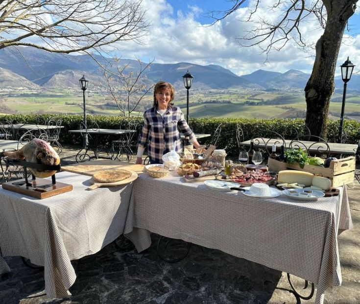Ein schön gedeckter Tisch mit regionalen Köstlichkeiten, umgeben von einer malerischen Hügel Landschaft.