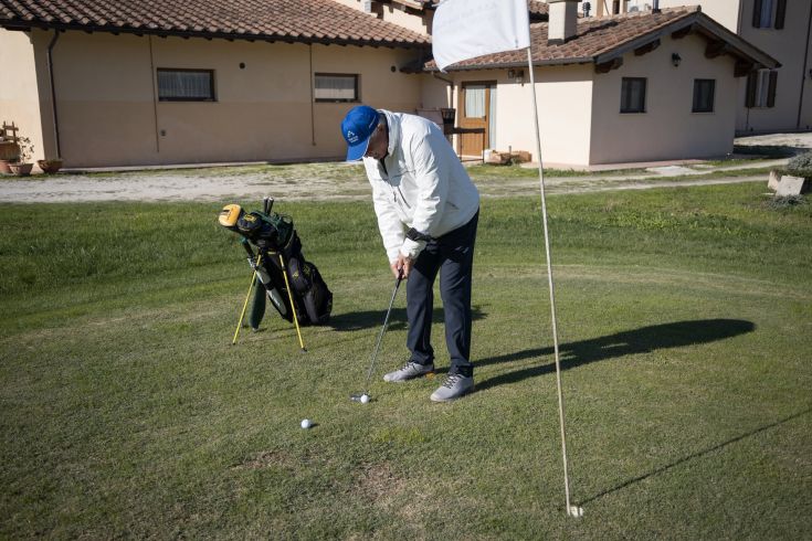Un golfista si accinge a effettuare un colpo in un campo da golf verde e luminoso.