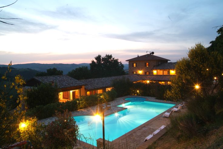 Una villa circondata dalla natura con piscina, illuminata dal calar del sole.