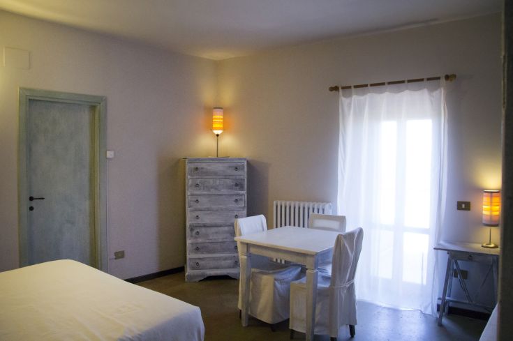 Camera spaziosa con arredi chiari e illuminazione naturale, creando un ambiente tranquillo.