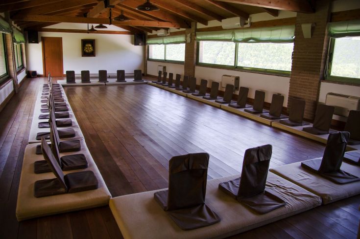 Uno spazio arredato con sedie e cuscini disposti in cerchio, adatto per incontri e pratiche di meditazione.