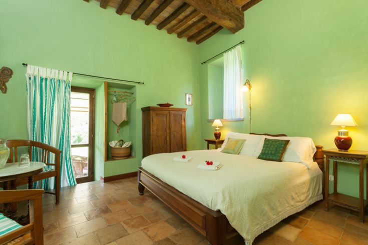 Camera semplice con pareti verdi, letti comodi e decorazioni rustiche. Un angolo tranquillo a contatto con la natura.