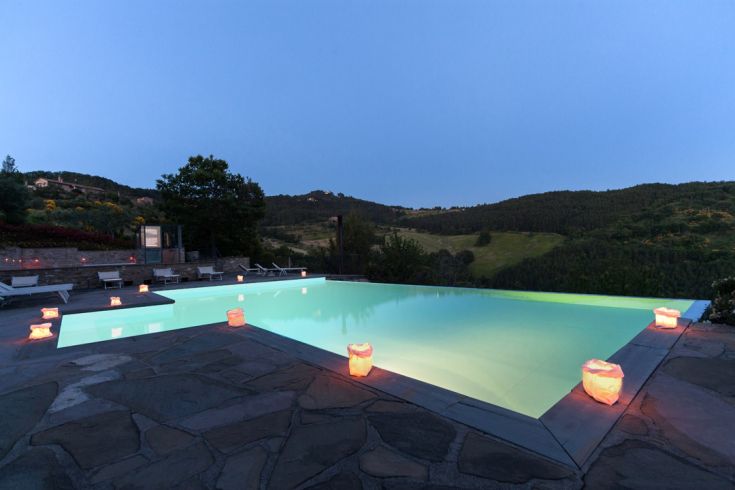Una piscina tranquilla circondata da vegetazione, con lanterne che creano un'atmosfera rilassante.