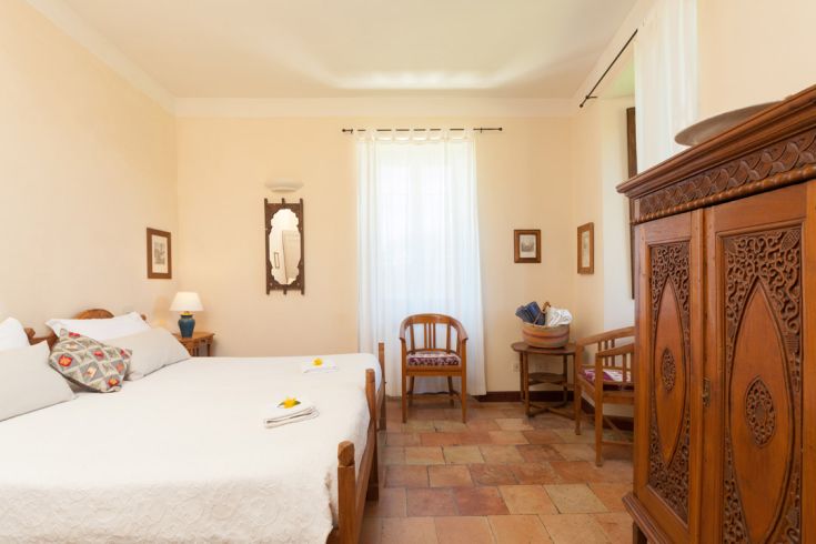 Camera semplice con letti matrimoniali e arredi in legno, ideale per un soggiorno tranquillo.