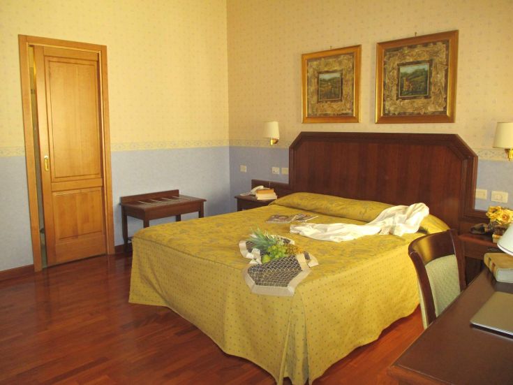Bequemes Hotelzimmer mit Holzfußboden und ordentlichem Mobiliar, ideal für einen Aufenthalt in Orvieto.