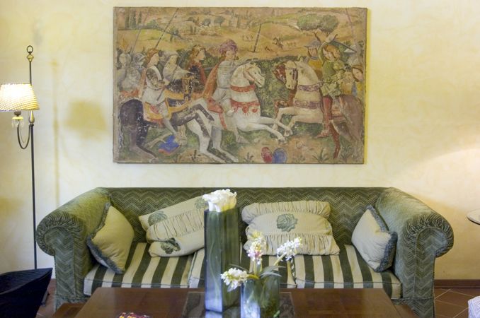 Ein gemütliches Wohnzimmer mit einem schlichten Sofa und einem Fresko, das eine historische Schlachtszene zeigt.