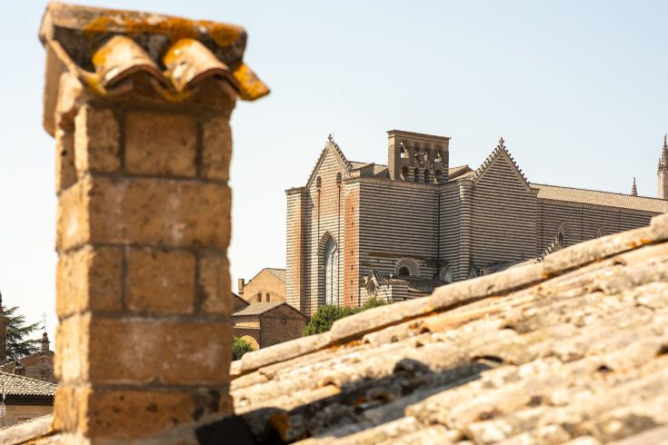 Scena del Duomo di Orvieto, affiancato da un camino in mattoni sullo sfondo.