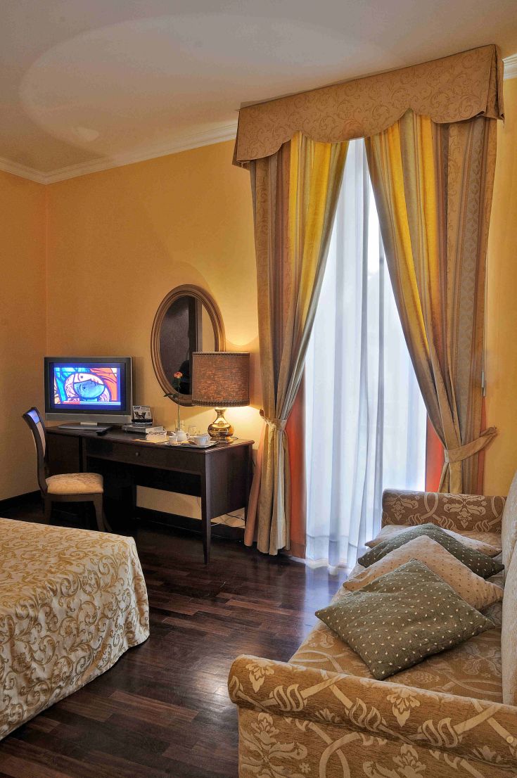 Camera confortevole con arredi semplici, dotata di televisione e area salotto, ideale per un soggiorno tranquillo.