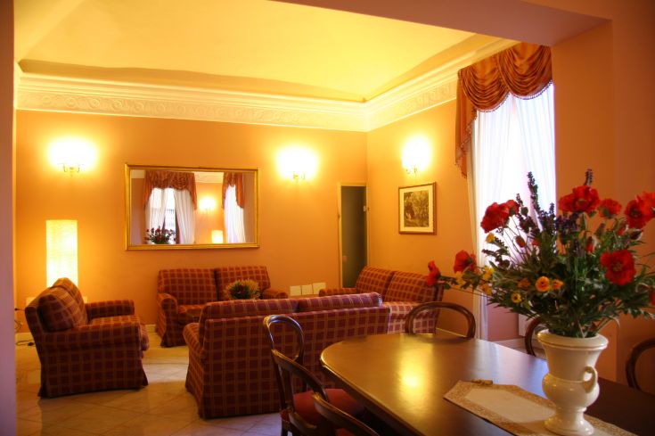 Soggiorno ben illuminato con arredamento classico, all'interno di un palazzo d'epoca.