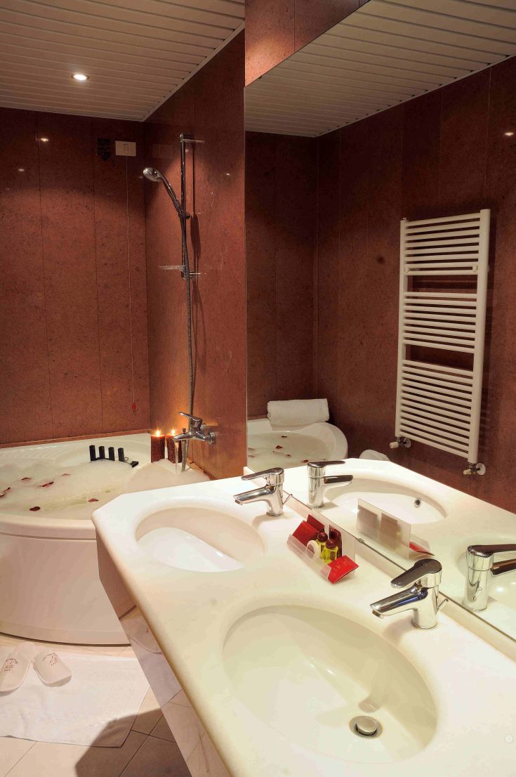 Bagno raffinato con vasca idromassaggio e dettagli in marmo chiaro.