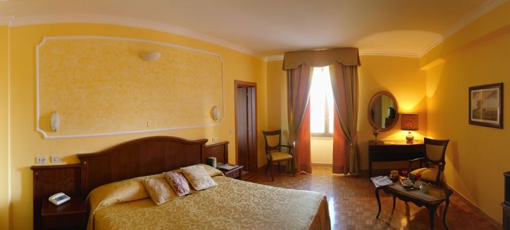 Interno di una camera con arredamento pratico, tonalità gialle e un'atmosfera accogliente.