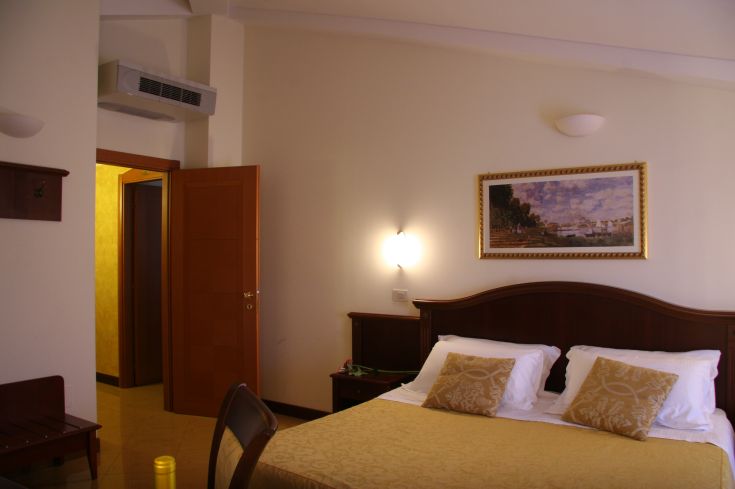 Stanza con letto matrimoniale e arredi semplici in un contesto classico.