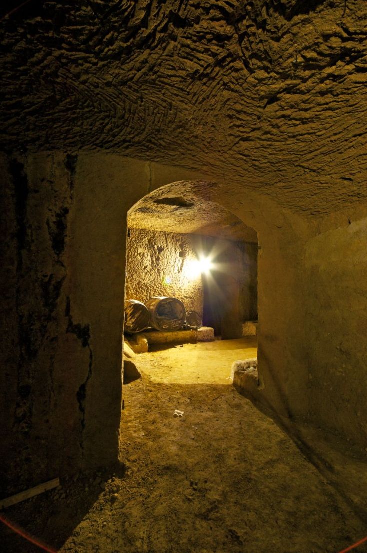 Un tunnel sotterraneo con pareti in roccia grezza, illuminato da una lampada. L'ambiente risulta suggestivo e accogliente.