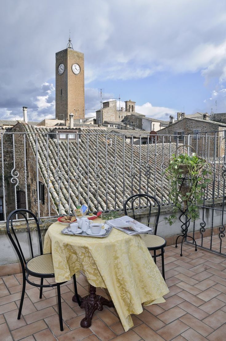 Una terrazza con panorama sulla città, tavolo apparecchiato per una colazione semplice.