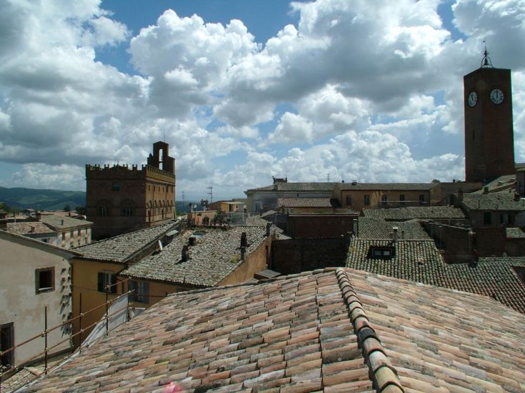 Panorama dei tetti e delle torri di un'antica città umbra sotto un cielo nuvoloso.