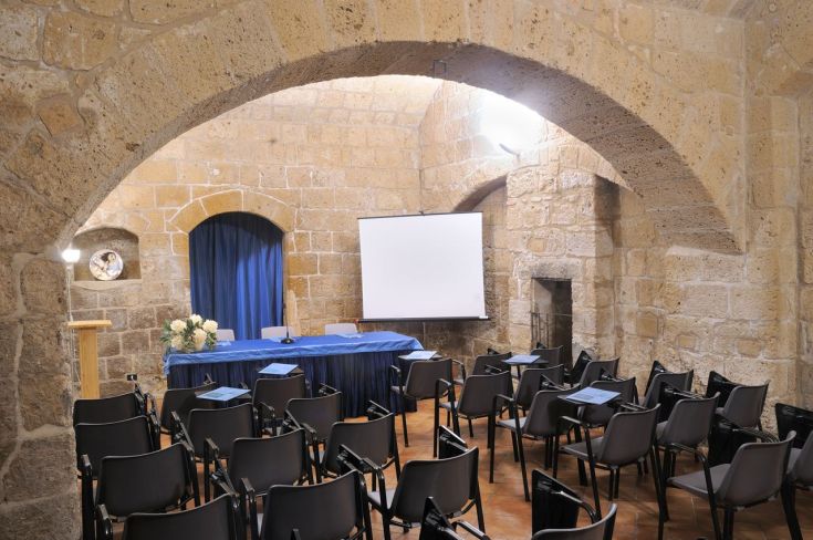 Ambiente suggestivo per conferenze, con pareti in pietra e allestimento per eventi.