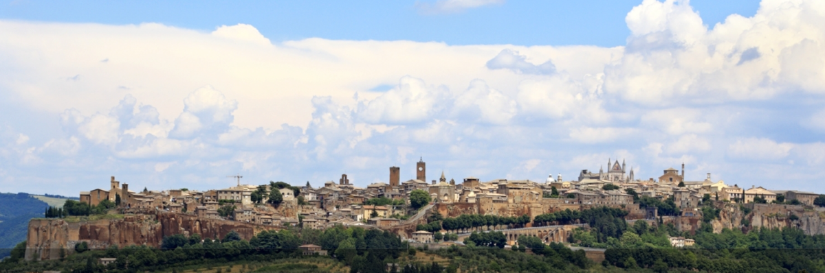 Un panorama di Orvieto che mostra edifici storici e un cielo sereno con alcune nuvole.