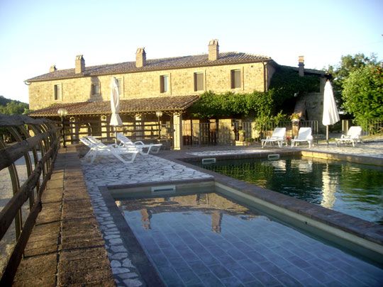 Ein Landhaus mit Pool, umgeben von Liegestühlen, in einer ruhigen natürlichen Umgebung.