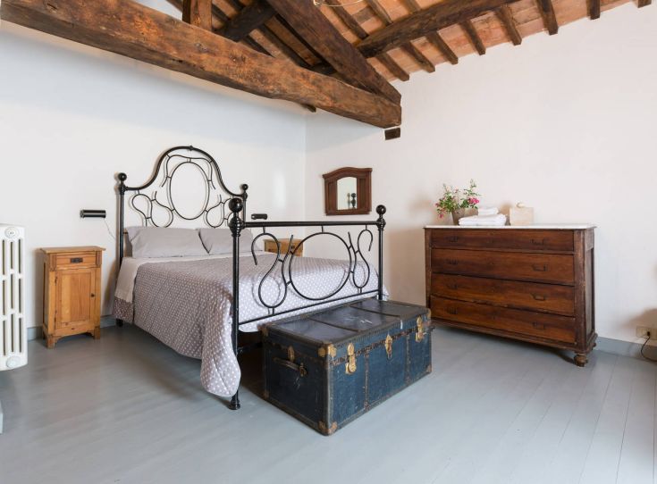 Camera semplice con letto in ferro e mobili in legno, ideale per un soggiorno tranquillo.