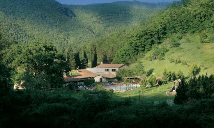 Ein historisches Gebäude in einem üppigen Tal, das in ein gemütliches Hotel umgewandelt wurde.