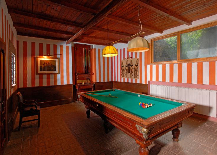 Ein gepflegter Billardraum mit Holzmöbeln und gestreiften Wänden, ideal um Zeit mit Freunden zu verbringen.