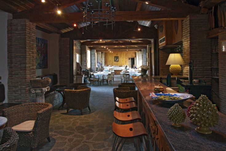 Innenszene eines einfachen Restaurants mit Holztischen und -stühlen, Ziegelwänden und warmen Lampen.