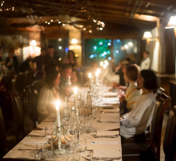 Gemütliche und warme Restaurantatmosphäre mit sanfter Beleuchtung und Kerzen auf den Tischen.