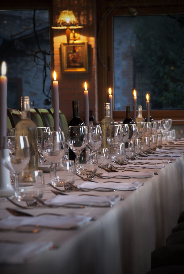 Ein wunderschön gedeckter Tisch mit brennenden Kerzen und Weinflaschen, perfekt für ein Abendessen mit Freunden.