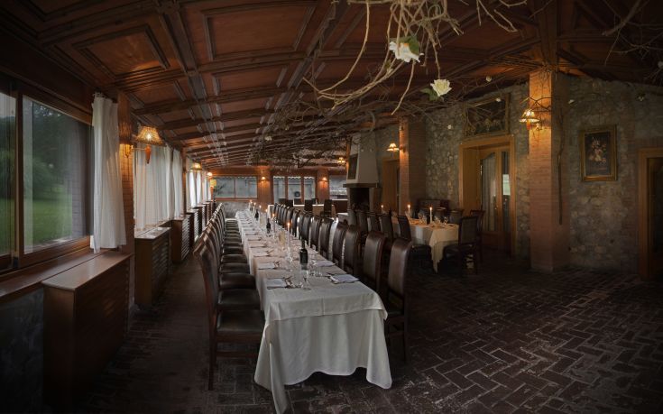 Ein Restaurant in einem historischen Bauernhaus, mit ordentlichen Tischen und umgeben von Grünflächen.