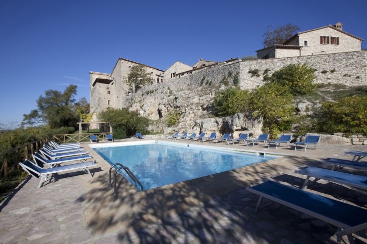 A swimming pool located in a natural setting, near an ancient village.
