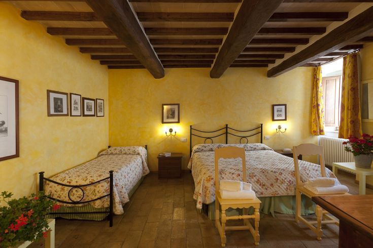 Simple room with single and double beds, decorated in a traditional style.