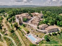 A historic building surrounded by lush greenery, featuring a swimming pool and outdoor activity spaces.