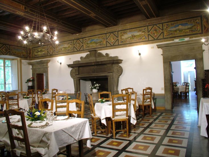 Spazio pranzo con tavoli ordinati e alcune decorazioni d'epoca sul muro.