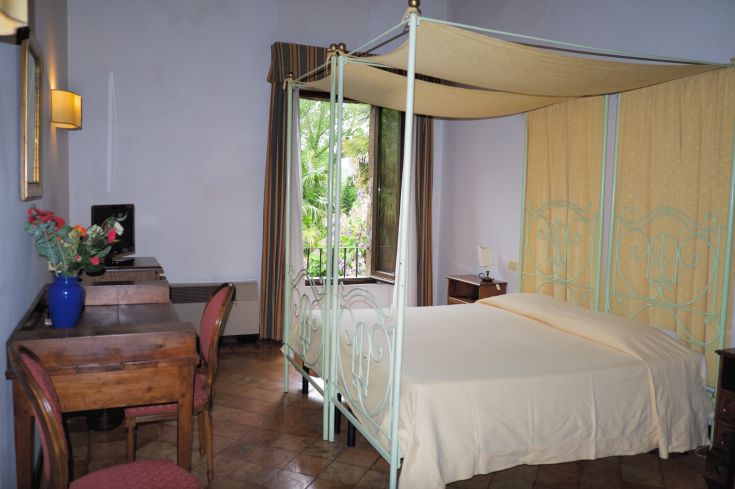 Camera di un hotel con letti matrimoniali e affaccio su un'area verde.