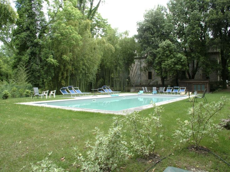 Una zona con piscina situata in un contesto naturale, circondata da un parco ben curato.