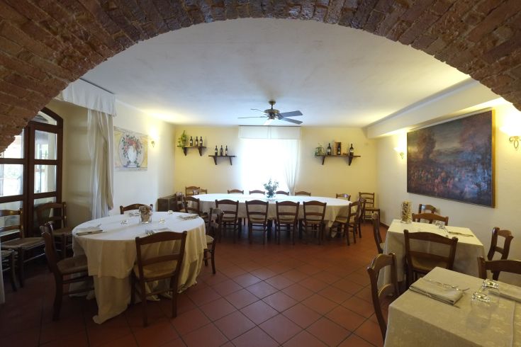 Interno di un ristorante con tavoli sistemati, arredamento semplice e soffitto a volta.