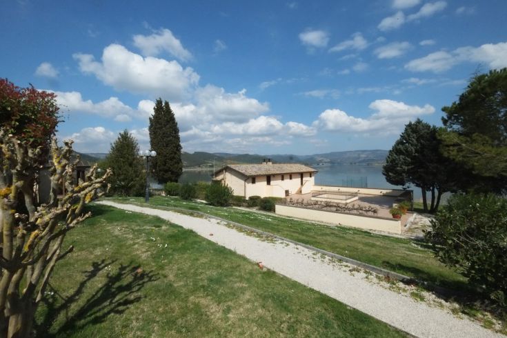 Scena di un albergo situato in un contesto naturale, circondato da alberi e verde.