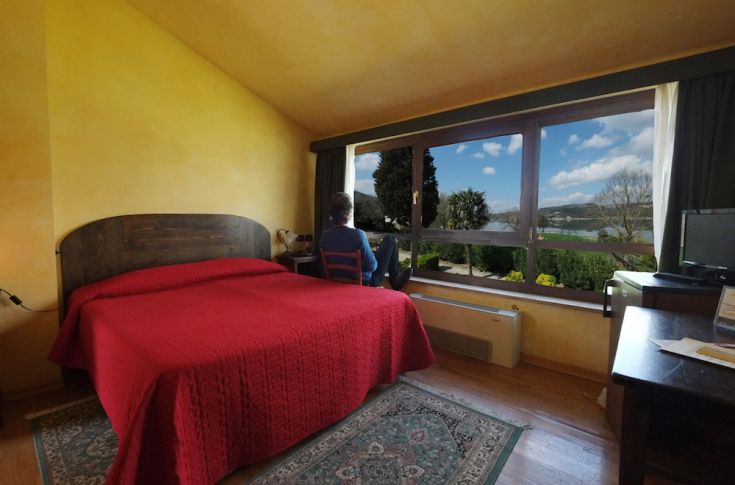 Camera accogliente con letto rosso e panorama su un paesaggio tranquillo.