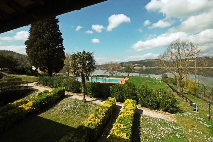 Un paesaggio tranquillo con piscina, circondato da alberi e con un panorama che si affaccia su un lago.