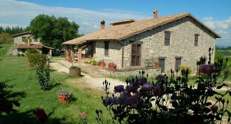 Una scena che mostra una casa in pietra immersa in un giardino ben curato e fiorito.