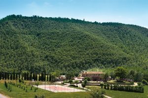 Un agriturismo circondato dal verde, con un panorama sulle colline e un campo da tennis.