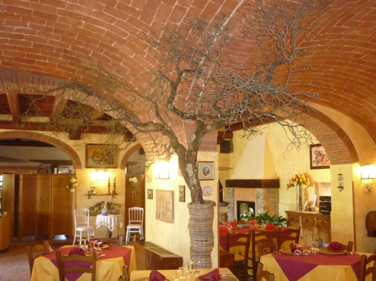Un ristorante con arredi semplici e un design rustico, caratterizzato da un albero decorativo centrale.