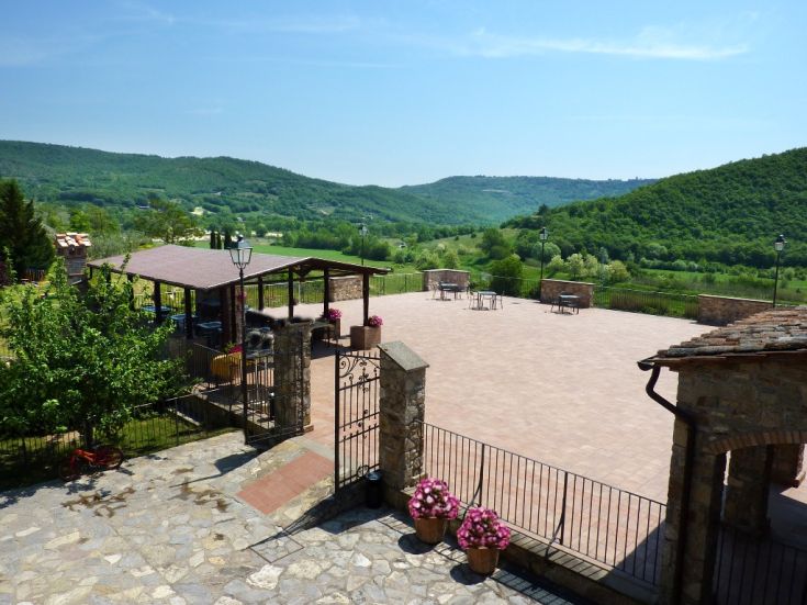 Ambiente sereno con una terrazza e un edificio rustico immerso nel verde circostante.