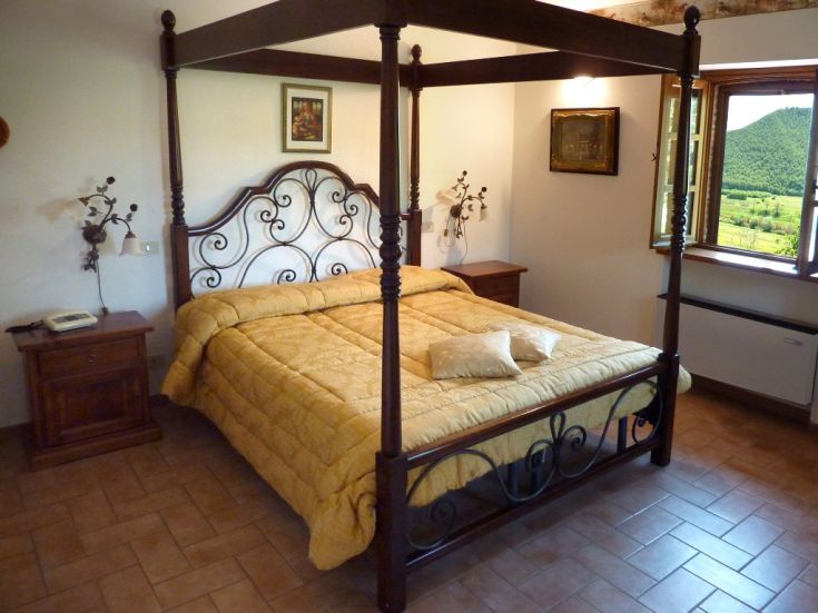 Camera da letto con letto a baldacchino e panorama sulla natura circostante.