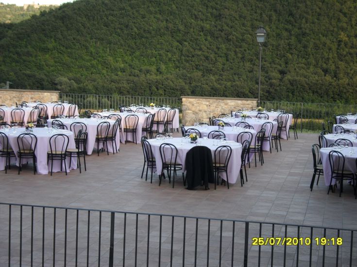 Un semplice allestimento di tavoli per eventi all'aperto, immersi in un contesto verde.