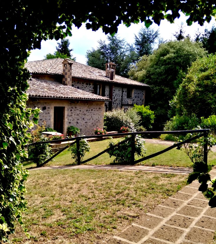 Szene einer Herberge, umgeben von Grün, mit Steinelementen.