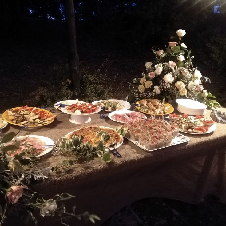 Ein im Freien schön arrangiertes Buffet mit einer Auswahl an verschiedenen Gerichten und einfachen Blumendekorationen.