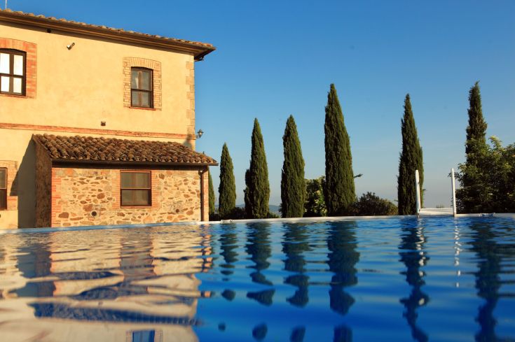Farmhouse with a pool surrounded by the typical natural landscape of the Umbrian countryside.