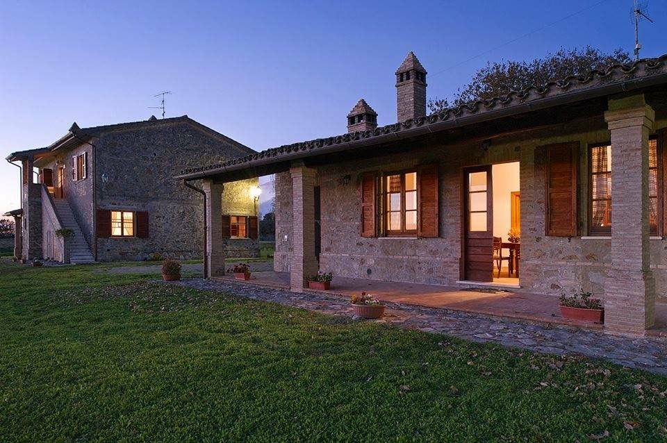 Agriturismo situato nell'Umbria, circondato da spazi verdi e antichi edifici in pietra.